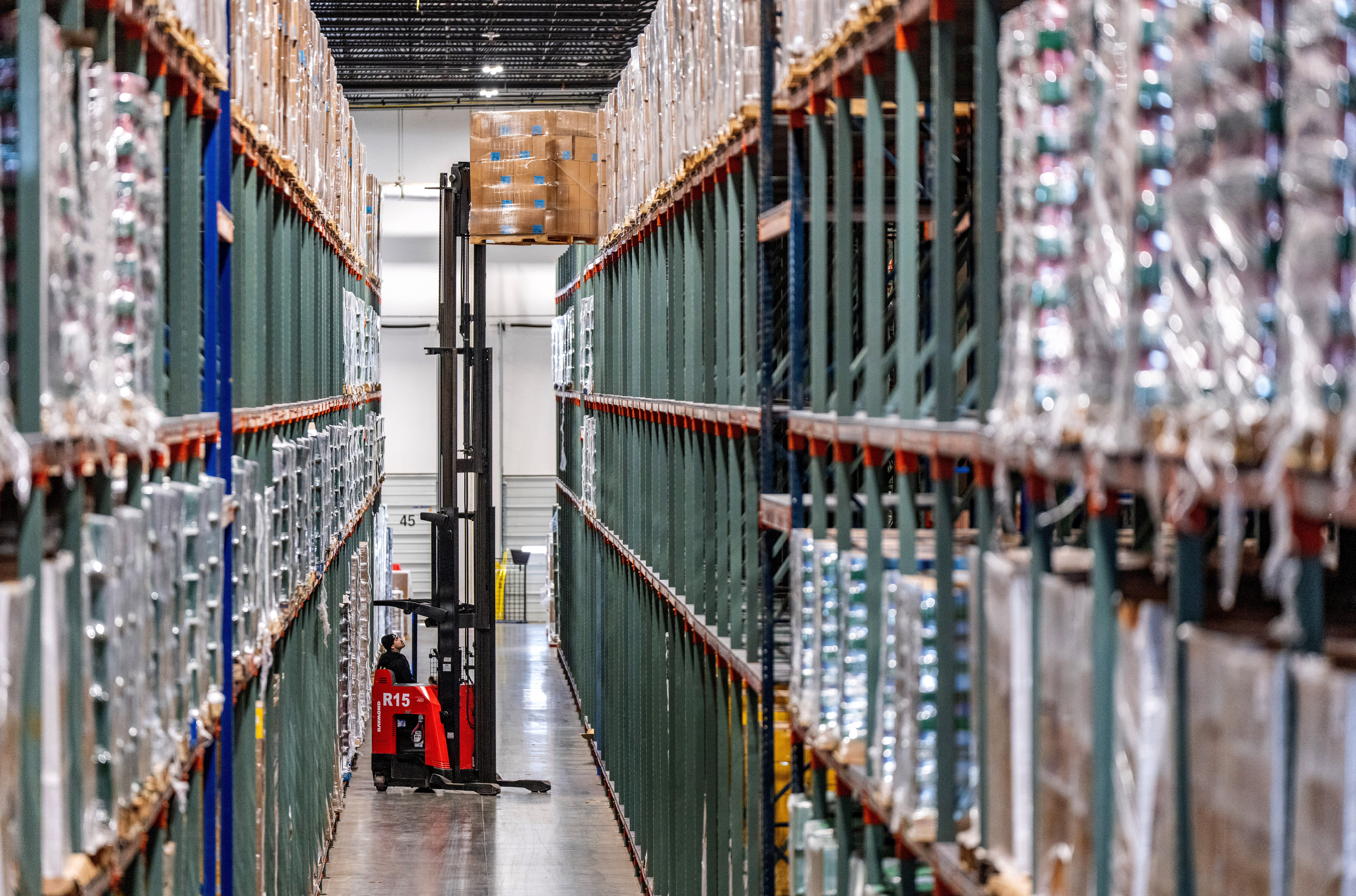 A forklift moves inventory to the top rack of a warehouse